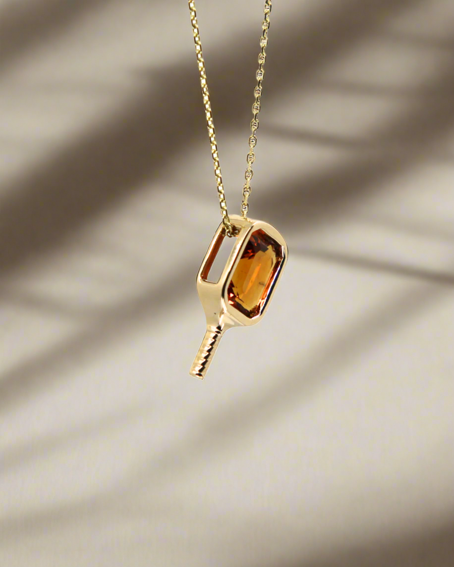 14k yellow Gold necklace with a pickleball paddle pendant featuring an orange citrine gemstone bezel set