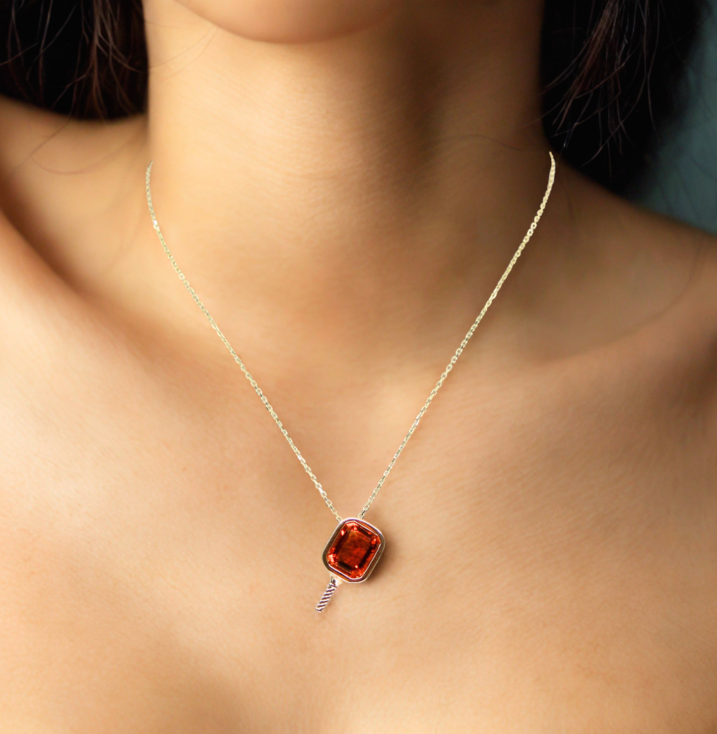 Necklace with a beautiful orange citrine bezel set in a pickleball paddle pendant on a person's neck