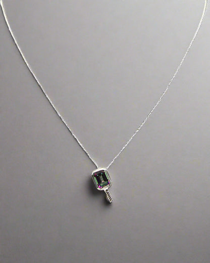 a beautiful pickleball shaped necklace set centrally with a mystic topaz gemstone that is a beautiful purple green color on a silver chain